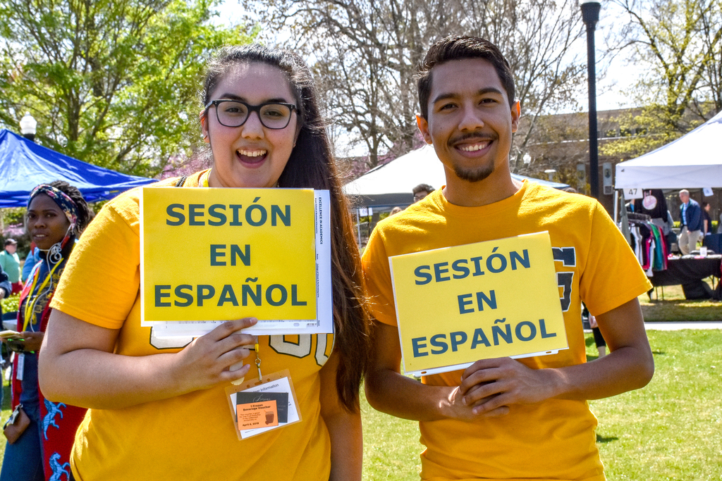 Two students holding signs that read Sesion en Espanol