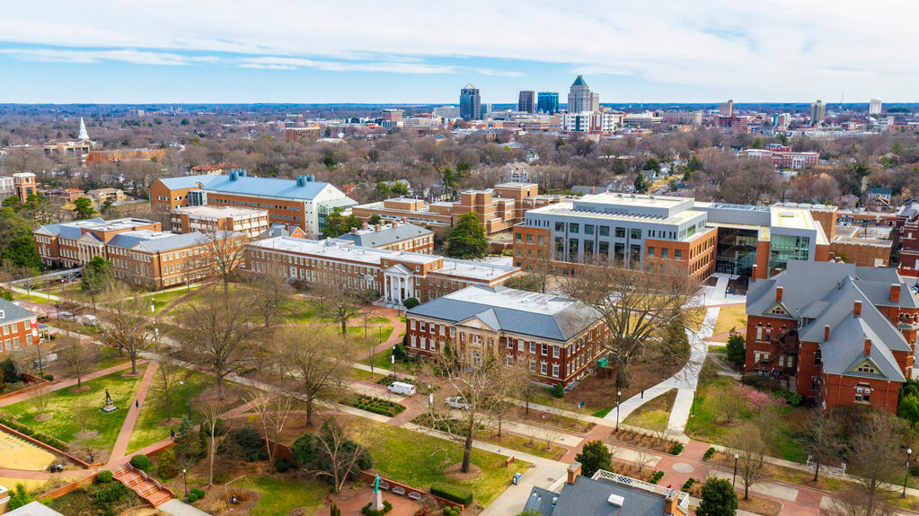 overhead view of UNCG campus, with the downtown Greensboro skyline in the background